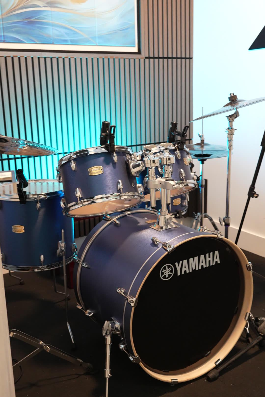 The blue Yamaha house kit against slat-wood acoustic panels